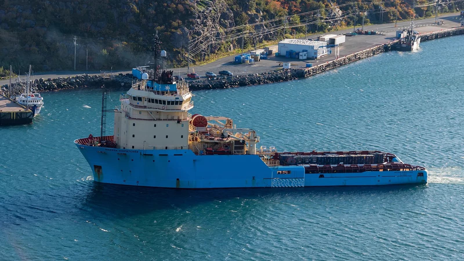 An offshore support vessel with a clear working deck manoeuvring in a harbour approach