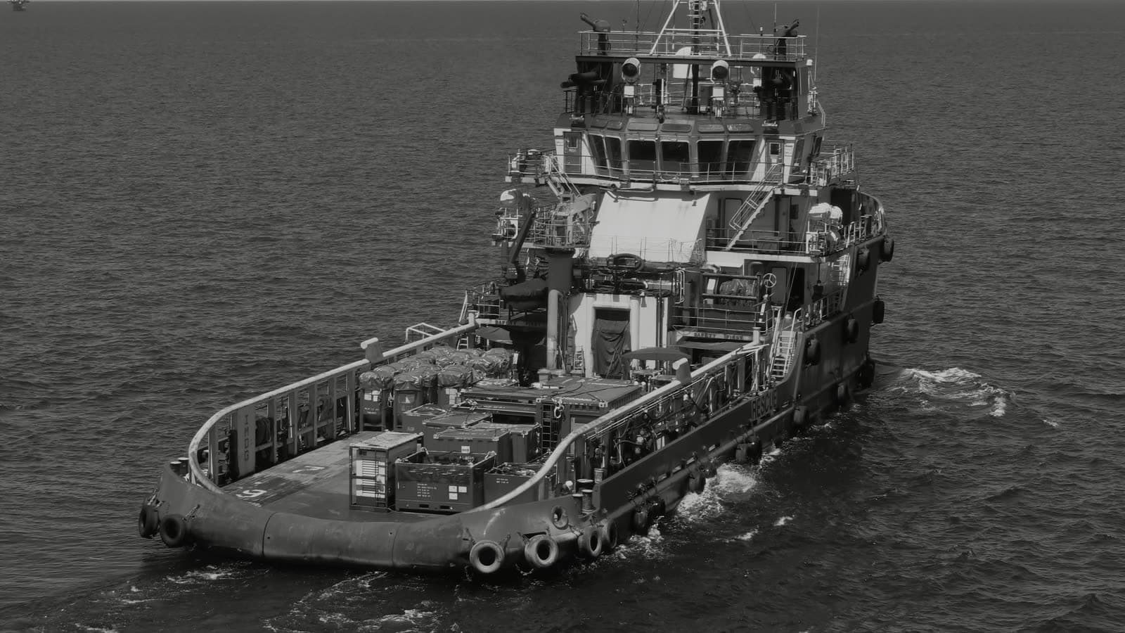 Offshore support vessel under way with deck cargo secured aft